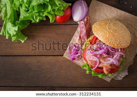 Big sandwich - hamburger burger with beef, red onion, tomato and fried bacon. Top view
