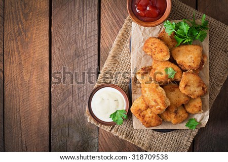 Chicken nuggets and sauce on a wooden background. Top view