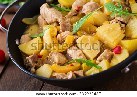 Stewed potatoes with meat and vegetables in a roasting tin on a wooden background