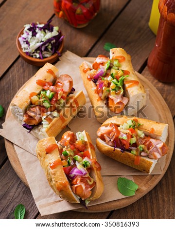 Hot dog - sandwich with Mexican salsa on wooden background.
