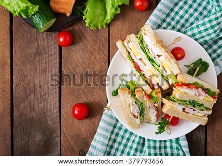 Club sandwich with cheese, cucumber, tomato, ham and eggs. Top view