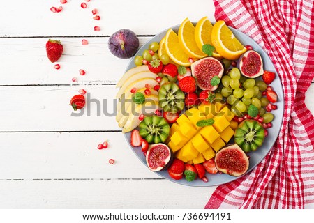 Platter fruits and berries. Mango, kiwi, fig, strawberry, grapes, pear and orange. Vegan cuisine. Dietary menu. Flat lay. Top view