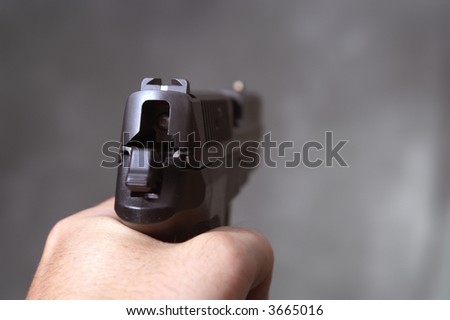 Man pointing semi automatic handgun away from camera