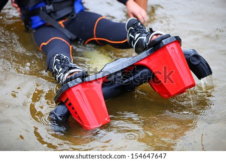 Cropped view of woman wearing flyboard boots and sitting in shallow water before a ride