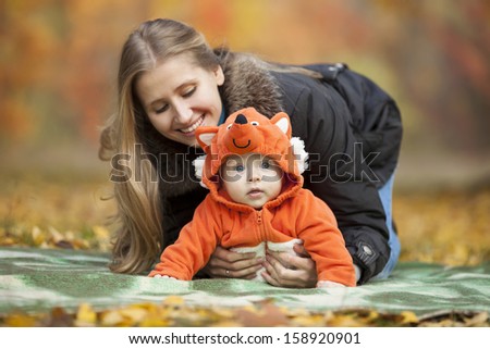 Young woman with baby dressed in fox costume having fun in autumn park