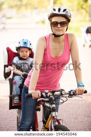 Caucasian young woman on a bicycle with little son behind