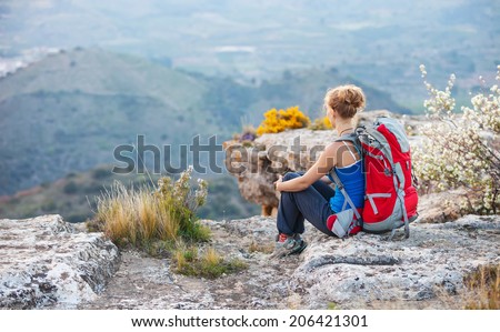 Woman tourist sitting on top of a mountain