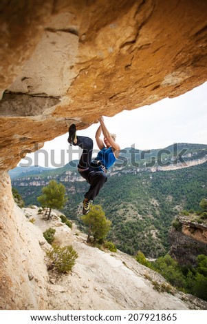 Female rock climber on overhanging cliff