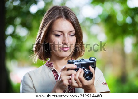 Young woman looking at screen of retro style camera and smiling