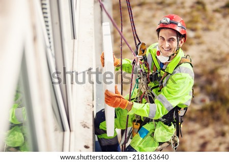 Industrial climber placing a polyfoam sheet insulation to the wall on a building