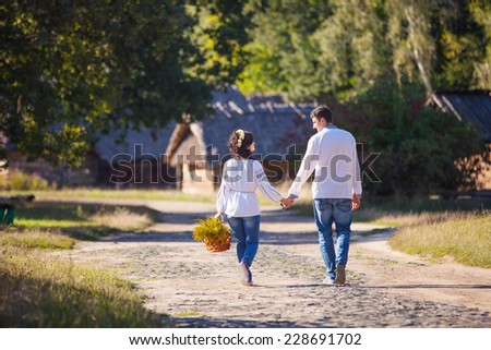 Young couple in Ukrainian style clothing walking along the road