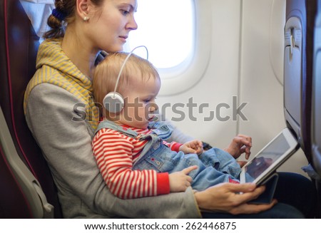 Caucasian mother and toddler son using tablet pc while on board of airplane
