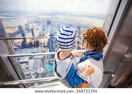 DUBAI, UAE - FEBRUARY 24: Young woman and her toddler son looking out of the window, while visiting At The Top - Observation Deck of Burj Khalifa. Picture taken on February 24, 2015.