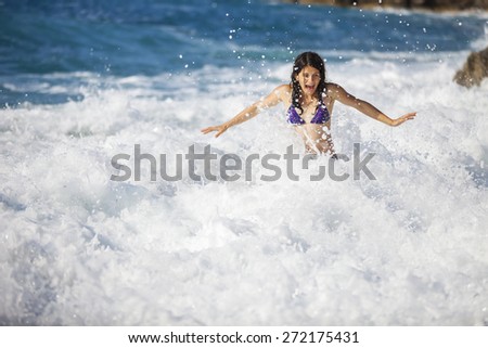 Young woman bathing in storming sea, high wave just washed her over