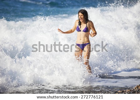 Young woman bathing in storming sea, high wave just washed her over