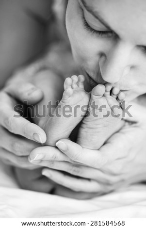 Closeup of mother holding and kissing newborn\'s feet