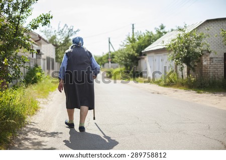 Senior woman walking down street in countryside