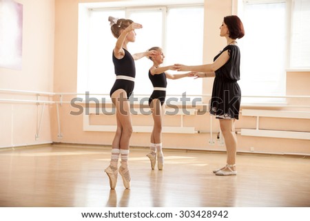 Ballet teacher helping young girls to dance en pointe