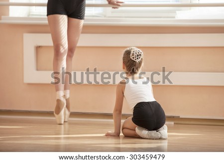 Girl beginner watching classmate standing en pointe in ballet dancing class