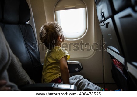 Little boy looking out of window in airplane