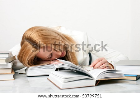 Young woman falling asleep while studying at the table with a lot of books, on white background