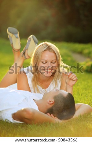 Young happy couple lying down on grass in the sun