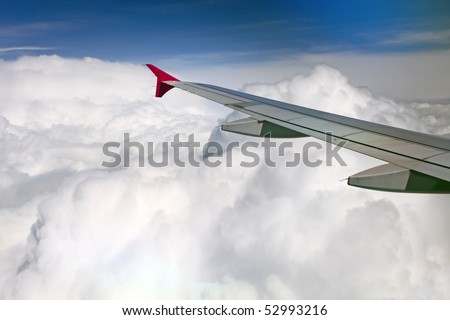 View of jet plane wing on the background of thick clouds and blue sky