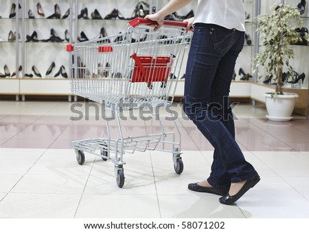Lower half waist down image of woman in jeans pushing a shopping cart in a shoe store