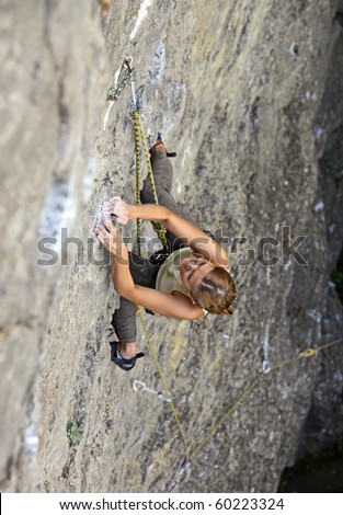 Female rock climber clinging to a cliff as she battles her way up