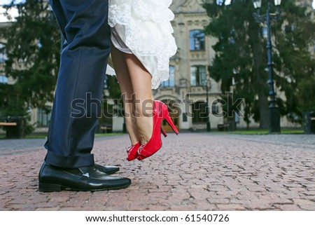 Groom lifting his bride up during their walk, close-up of lower part of the bodies