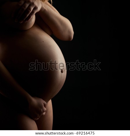 stock photo A naked pregnant woman on black background