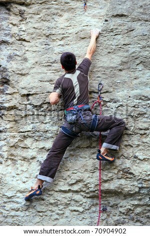 Rock climber climbing up a cliff