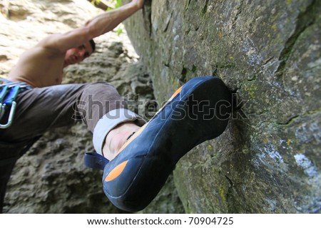 Rock climber about to start climbing his route, bottom view with his foot on the foreground