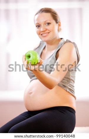 Young pregnant woman holding green apple, healthy pregnancy concept