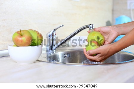 Cropped image of woman washing apples, hands in focus