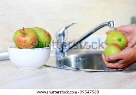 Cropped image of woman washing apples, bowl with apples in focus