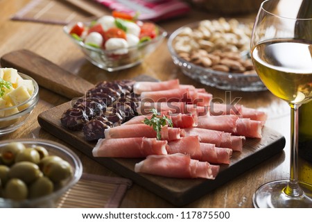 Full table of prosciutto, olives, cheese, salad and wine