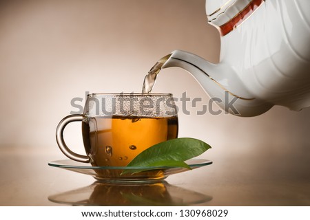 Hot green tea pouring in to cup close up