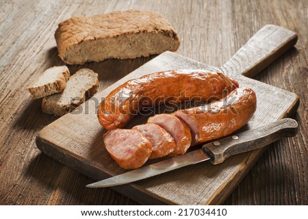 the sliced tasty sausage with bread on the wooden table