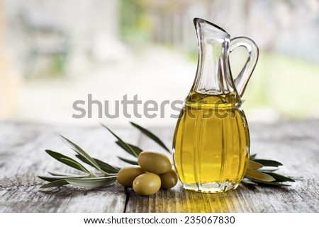 Olive oil and olive branch on the wooden table outside