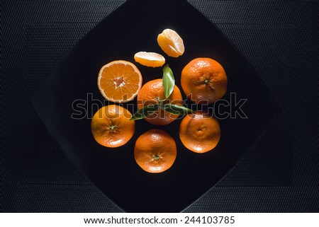 ripe juicy tangerine, orange mandarin with leaves on black table