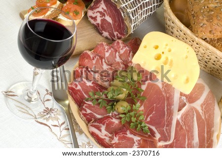 arranged prosciutto, wine, olives cheese, bread and tomato close up