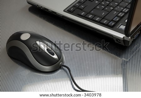 laptop computer with mouse on reflective surface close up
