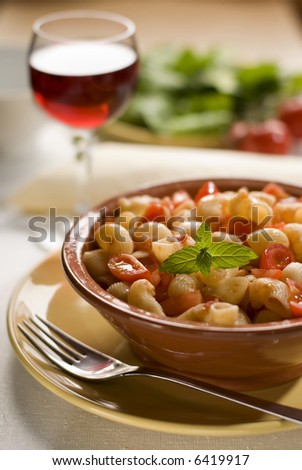 macaroni with tomato sauce and salad in background