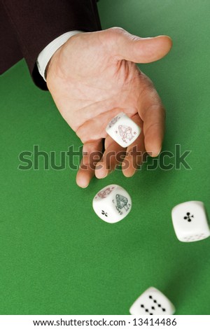Hand rolling dices on green table close up