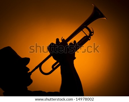 back light musician playing trumpet on orange background