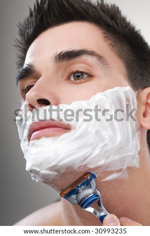 Young Man shaving with razor close up