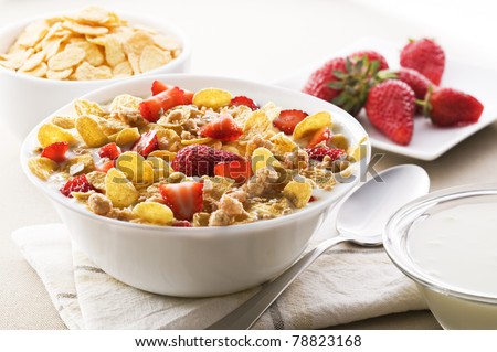 Fresh corn flakes with strawberries and milk close up