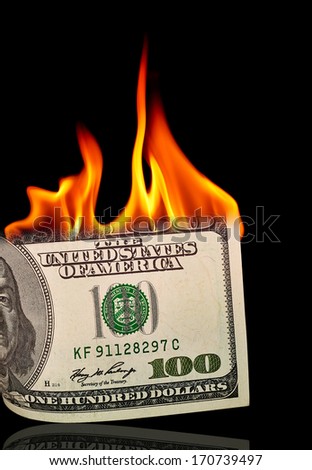 Dollar bill burning on black background