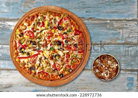 Pizza and cola with ice on grungy background from top